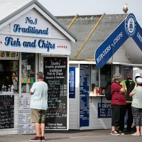 Man looks at the menu at a fish and chip takeaway hut as visitors take advantage of the fine weather at West Bay on September 1, 2016 in Dorset,...