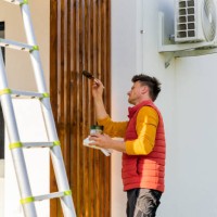 man painting wooden columns of modern villa while standing by ladder - home decoration stock pictures, royalty-free photos & images