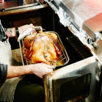 man pulling cooked turkey out of oven - food stock pictures, royalty-free photos & images