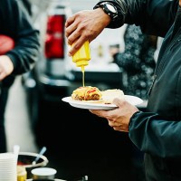 man putting mustard on burger at tailgating party - food stock pictures, royalty-free photos & images