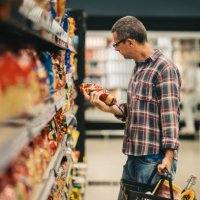 man reading a label while grocery shopping in a supermarket aisle - food stock pictures, royalty-free photos & images