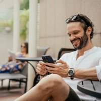 man relaxing by the pool using smartphone - travel stock pictures, royalty-free photos & images