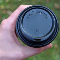 man's hand holding a disposable coffee cup with a black plastic lid - junk food stock pictures, royalty-free photos & images