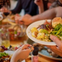 man serving himself at friendsgiving potluck dinner - food stock pictures, royalty-free photos & images