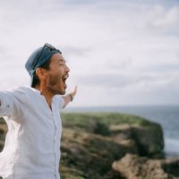 man shouting on top of cliff by sea - travel stock pictures, royalty-free photos & images