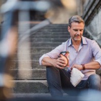 man sitting on stairs with takeaway coffee in the city checking the time - junk food stock pictures, royalty-free photos & images