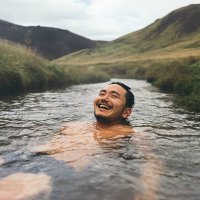 man soaking in natural hot spring surrounded by nature in iceland - travel stock pictures, royalty-free photos & images