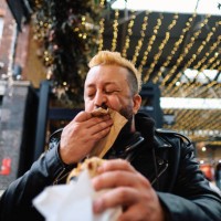 man spontaneously cleans mouth with napkin while enjoying food market fare. - food stock pictures, royalty-free photos & images