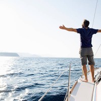 man stands at bow of yacht with arms outstretched - travel stock pictures, royalty-free photos & images