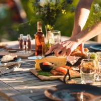 man taking a slice of cheese at midsummer dinner - garden decoration stock pictures, royalty-free photos & images