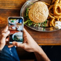man talking picture of burger with smartphone - junk food stock pictures, royalty-free photos & images