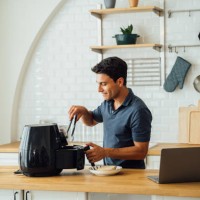 man using air fryer and laptop in kitchen - food stock pictures, royalty-free photos & images