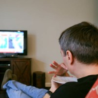 man watches tv while eating snack - junk food stock pictures, royalty-free photos & images