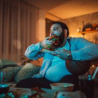 man watching a sports match and eating burger - junk food stock pictures, royalty-free photos & images