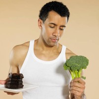 man with broccoli and chocolate cake - junk food stock pictures, royalty-free photos & images