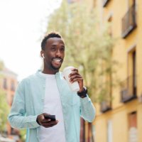 man with in-ear headphones holding reusable cup at street - junk food stock pictures, royalty-free photos & images