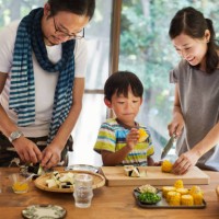 man, woman and boy standing at a table, preparing corn on the cob, smiling. - food stock pictures, royalty-free photos & images