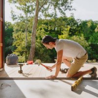 man working on wooden decking in front of a cabin house - home decoration stock pictures, royalty-free photos & images
