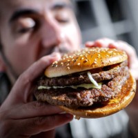 March 2025, Bremen: ILLUSTRATION - A man bites into a burger. Photo: Sina Schuldt/dpa