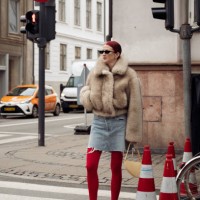 Marianne Theodorsen wears red tights, red shoes, a denim mini skirt, a brown fur coat, and a pale yellow bag outside The Garment during the...