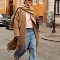 Marianne Theodorsen wears wide jeans, a brown coat, and orange sunglasses outside Lovechild 1979 during the Copenhagen Fashion Week AW24 on January...