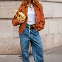 Marie Gaguech wears white tank top, orange shirt, blue jeans, yellow Miu Miu bag, brown loafers, outside Miu Miu, during the Womenswear Fall/Winter...