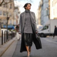 Mary Leest wears a gray wool turtleneck oversized pullover, a pale gray glitter wool long coat, a black shiny leather embossed checkered pattern...