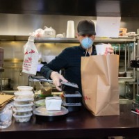 masked and gloved restaurant worker packaging food for delivery during covid-19 outbreak - junk food stock pictures, royalty-free photos & images