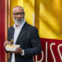 mature businessman eating french fries in front of snack bar - junk food stockfoto's en -beelden