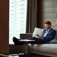 mature businessman texting on phone in hotel room - travel stock pictures, royalty-free photos & images