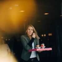 mature businesswoman talking on smart phone while holding food and drink against cafe - junk food stock pictures, royalty-free photos & images