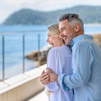 mature couple embracing on a waterfront balcony. - travel stock pictures, royalty-free photos & images