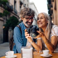 mature couple on vacation enjoying at the cafe and watching their photos - travel stock pictures, royalty-free photos & images