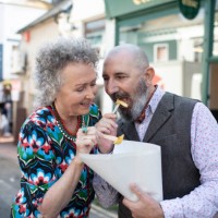 mature couple sharing a bag of chips outdoors - junk food stock pictures, royalty-free photos & images