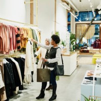 mature female friends looking at coat while shopping together in clothing boutique - fashion stock-fotos und bilder