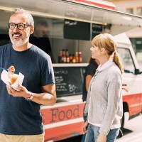 mature man eating food while standing against truck at street - junk food stock pictures, royalty-free photos & images