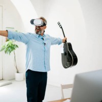 mature man playing the acoustic guitar in virtual reality glasses at the office - concert stock pictures, royalty-free photos & images