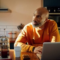 mature man using laptop at kitchen island - home decoration photos et images de collection