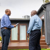 mature salesman holding digital tablet while discussing with male customer outside house - home decoration stock pictures, royalty-free photos & images