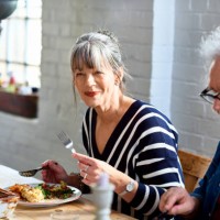 mature woman enjoying healthy lunch with friends - food stockfoto's en -beelden