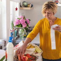 mature woman going through her receipts at home after buying groceries - food stock pictures, royalty-free photos & images