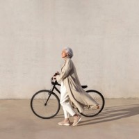mature woman walking with bicycle on footpath during sunny day - fashion photos et images de collection