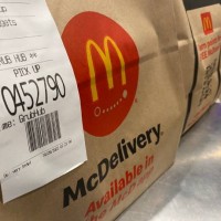 McDelivery Pick up food order bags at McDonald's fast food restaurant, Queens, New York.