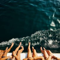 medium shot of teenagers feet hanging over side of sailboat - travel stockfoto's en -beelden