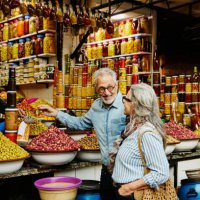 medium wide shot couple sampling olives in the medina of marrakech - travel stock pictures, royalty-free photos & images