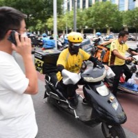 Meituan food couriers ride electric bicycles along a street on September 11, 2020 in Beijing, China.