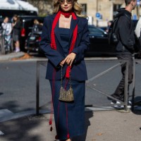 Merve Görgöz wears navy blazer, dress, red scarf, Miu Miu sunglasses, sequined Paco Rabanne bag, heels outside Miu Miu during the Womenswear...