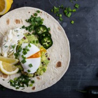 mexican style breakfast with poached egg, guacamole and coleslaw on flour tortilla - junk food stock pictures, royalty-free photos & images