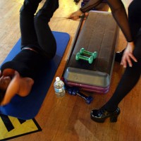 Michelle Fernandez uses her riding crop to help Myriam Fridman with her situps during an aerobics class called Whipped at Crunch October 25, 2002 in...