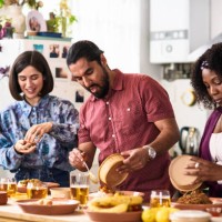mid adult man and two female friends serving takeaway food at home - junk food stock pictures, royalty-free photos & images